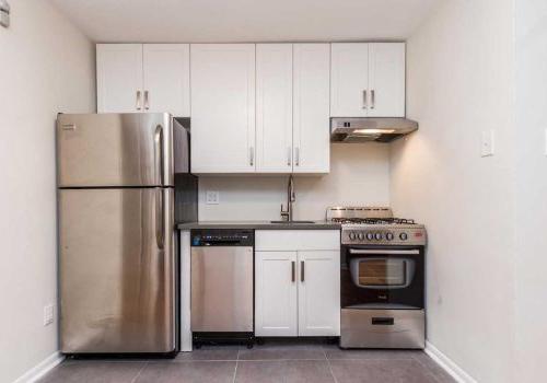更新的厨房配有不锈钢电器，灰色瓷砖地板和白色摇床橱柜.